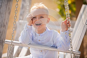 Child swing on backyard. Kid playing oudoor. Happy cute little boy swinging and having fun healthy summer vacation