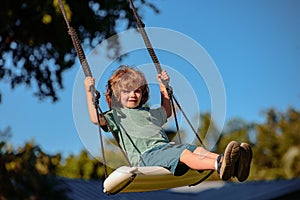 Child swing on backyard. Kid playing oudoor. Happy cute little boy swinging and having fun healthy summer vacation
