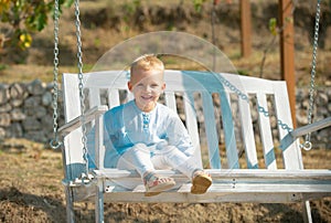 Child swing on backyard. Kid playing oudoor. Happy cute little boy swinging and having fun healthy summer vacation photo