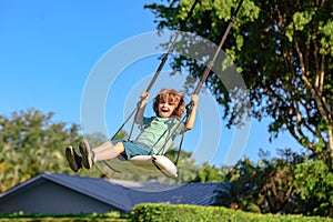 Child swing outdoor. Kid playing on backyard. Happy cute little boy swinging and having fun healthy summer vacation