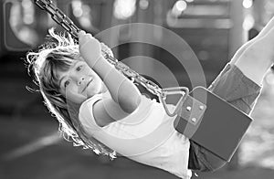 Child swinging on the playground. Cute little kid boy funny while playing on the playground. Summer, childhood, leisure