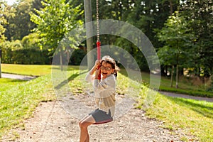 Child swinging on a swing in the park. Kid having fun outdoors