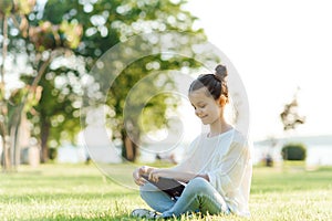 Child with tablet pc outdoors. Little girl on grass with computer