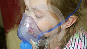 Child with tablet is sick and breathes through an inhaler. close-up. little girl treated with an inhalation mask on her