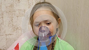 Child with tablet is sick and breathes through an inhaler. close-up. little girl treated with an inhalation mask on her