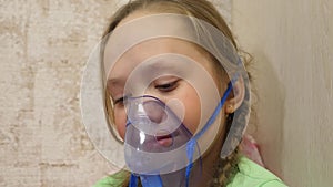 Child with tablet is sick and breathes through an inhaler. close-up. little girl treated with an inhalation mask on her