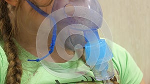 Child with tablet is sick and breathes through an inhaler. close-up. little girl treated with an inhalation mask on her