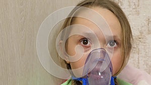 Child with tablet is sick and breathes through an inhaler. Close-up. Little girl treated with an inhalation mask on her