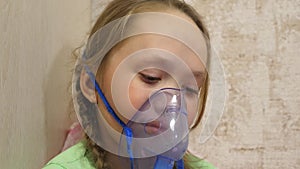 Child with tablet is sick and breathes through an inhaler. close-up. little girl treated with an inhalation mask on her