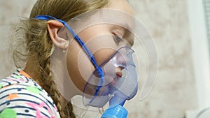 Child with tablet is sick and breathes through an inhaler. close-up. little girl treated with an inhalation mask on her