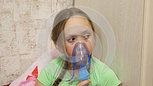 Child with tablet is sick and breathes through an inhaler. close-up. little girl treated with an inhalation mask on her