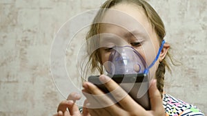 Child with tablet is sick and breathes through an inhaler. close-up. little girl treated with an inhalation mask on her
