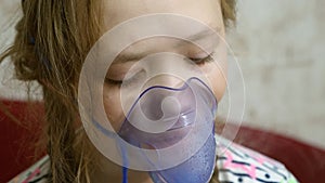 Child with tablet is sick and breathes through an inhaler. close-up. little girl treated with an inhalation mask on her