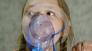 Child with tablet is sick and breathes through an inhaler. Close-up. Little girl treated with an inhalation mask on her
