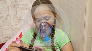 Child with tablet is sick and breathes through an inhaler. close-up. little girl treated with an inhalation mask on her