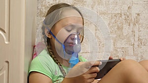 Child with tablet is sick and breathes through an inhaler. close-up. little girl treated with an inhalation mask on her