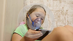 Child with tablet is sick and breathes through an inhaler. close-up. little girl treated with an inhalation mask on her