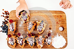 Child take berry cake from board, flat lay