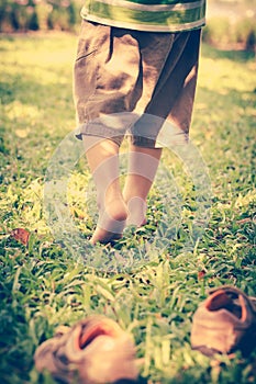 Child take off shoes. Child's foot learns to walk on grass