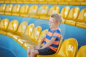 Child take own seat in the stadium or dolphinarium and waiting p