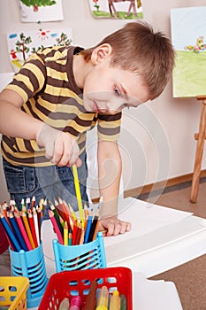 Child take pencil in play room.