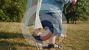 Child takes the first steps walking in the park with mom.