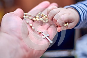 A child takes a rosary from his dad`s hand