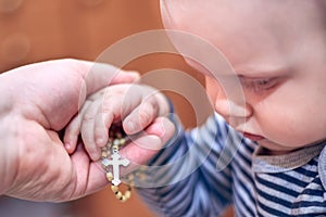 A child takes a rosary from his dad`s hand