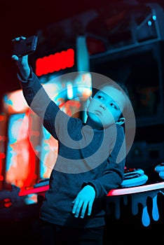 A child takes a selfie. The boy holds the phone in his hands. Neon lighting. Mobile games