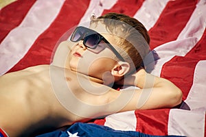 The child takes a sun bath on the beach