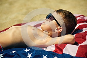 The child takes a sun bath on the beach