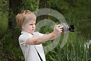 The child is taking pictures. Young photographer. The child looks at the camera screen