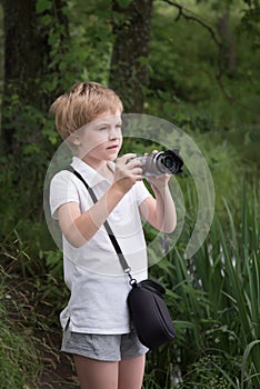 The child is taking pictures. Young photographer. The child looks at the camera screen