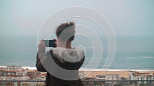 Child taking scenic shots of ocean coast in Nazare, Portugal