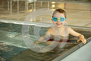 Child, taking swimming lessons in a group of children in indoor pool