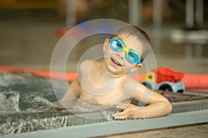 Child, taking swimming lessons in a group of children in indoor pool