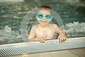 Child, taking swimming lessons in a group of children in indoor pool