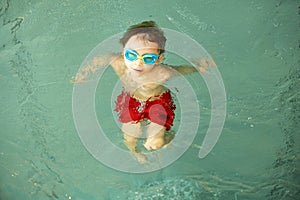 Child, taking swimming lessons in a group of children in indoor pool