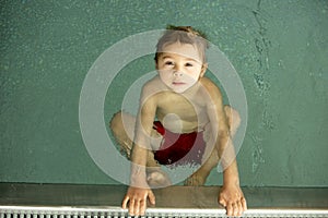 Child, taking swimming lessons in a group of children in indoor pool