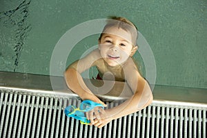 Child, taking swimming lessons in a group of children in indoor pool