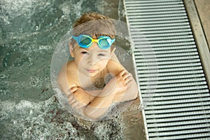 Child, taking swimming lessons in a group of children in indoor pool