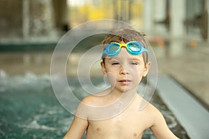 Child, taking swimming lessons in a group of children in indoor pool