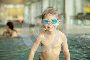 Child, taking swimming lessons in a group of children in indoor pool