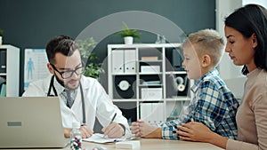 Child talking to friendly children`s doctor in hospital while mother laughing