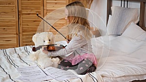 Child Teaching Teddy Bear to Play Violin Indoors