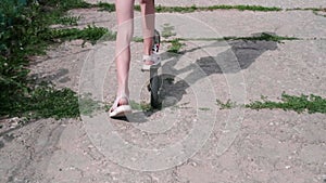 A child, a teenage girl rides a scooter on a sunny day. Slow motion.