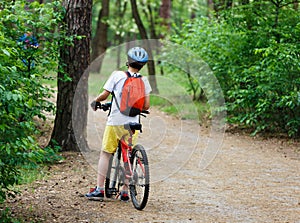Child teenager on bicycle ride in forest at spring or summer. Happy smiling Boy cycling outdoors in blue helmet. Active lifestyle