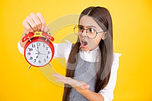 Child teenager girl with alrm clock isolated on yellow background. Time and deadline concept. Angry face, upset emotions