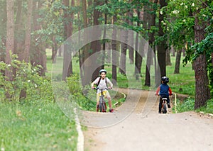 Child teenager in white t shirt and yellow shorts on bicycle ride in forest at spring or summer. Happy smiling Boy cycling