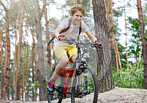 Child teenager in white t shirt and yellow shorts on bicycle ride in forest at spring or summer. Happy smiling Boy cycling outdoor